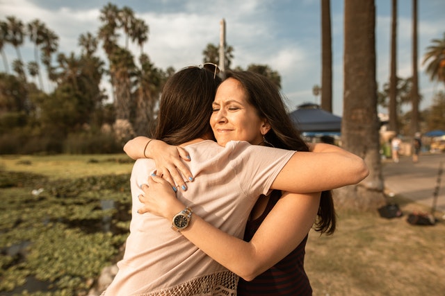 Aloha at Home - Positive supports are needed for parents. Two friends hug.